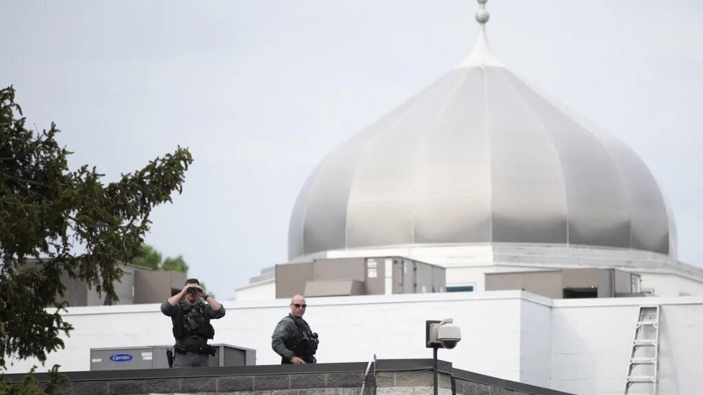Police officers stand on the roof of a mosque as Canada Prime Minister Justin Trudeau attends a vigil for the victims of the deadly vehicle attack in London, Ontario on 8 June 2021