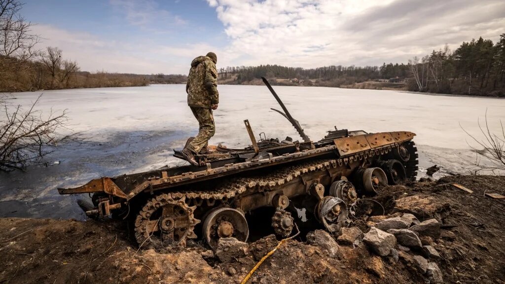 Un militaire ukrainien se tient près d’un char russe détruit dans la ville de Trostyanets, dans le nord-est du pays, le 29 mars 2022 (AFP/Fadel Senna)