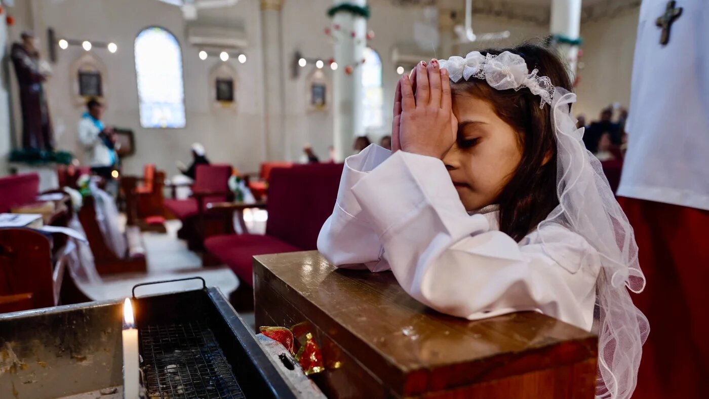 A young Christian girl prays during Christmas celebrations at the Holy Family Church in Gaza City on 21 December 2025 (Omar Al-Qattaa/AFP)