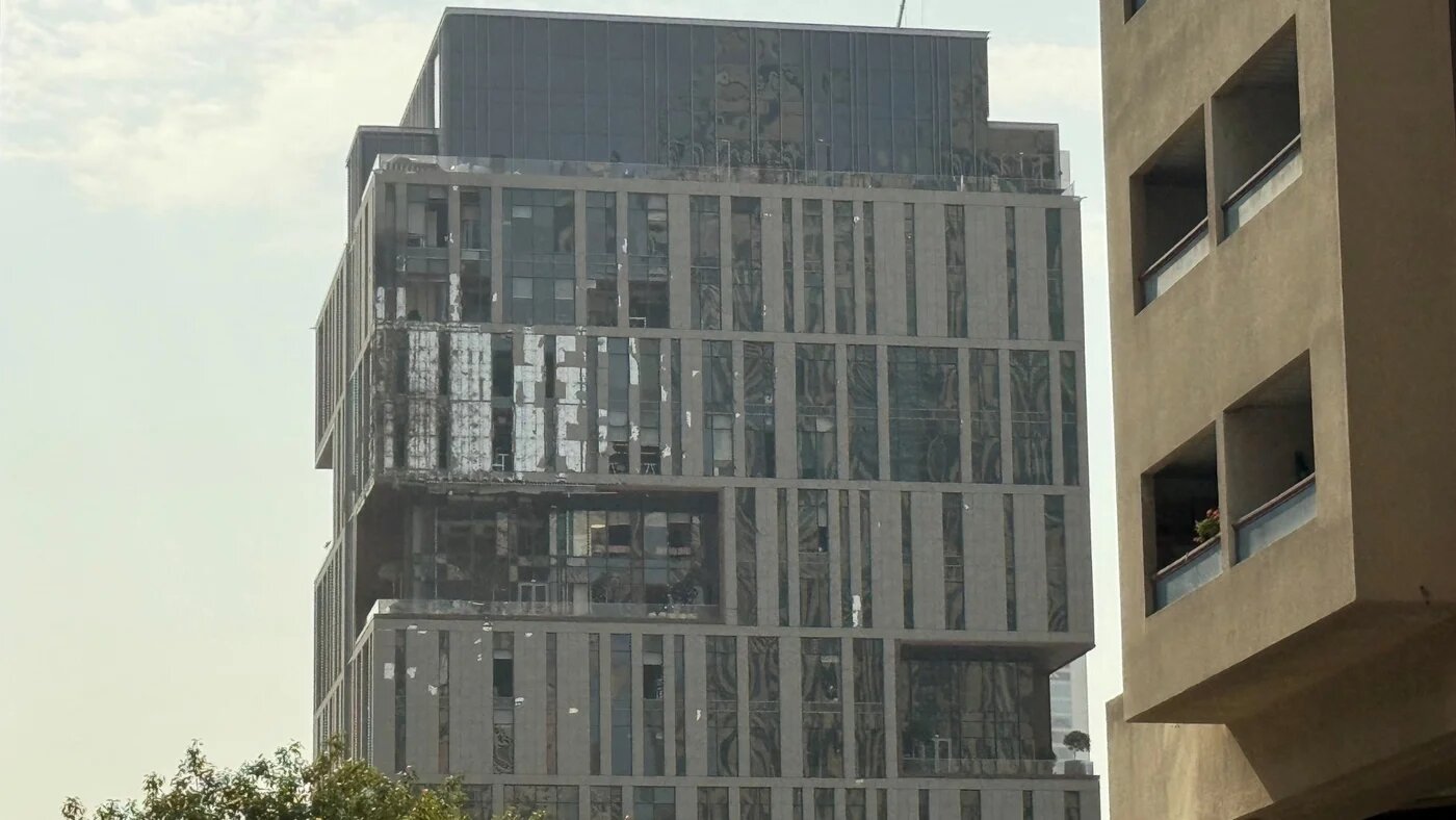 A damaged building in the Dubai International Financial Centre, after debris from a successful interception caused damage to the facade on 13 March 2026 (Reuters)