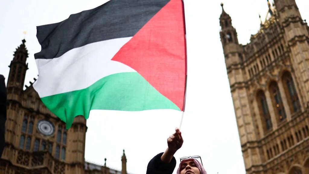 A demonstrator waves a Palestinian flag during a protest in Parliament Square, London, 21 February 2024 (Henry Nicholls/AFP)