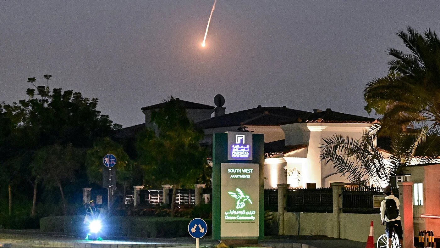 A cyclist watches as a projectile falls over Dubai on 28 February 28, 2026 (AFP)