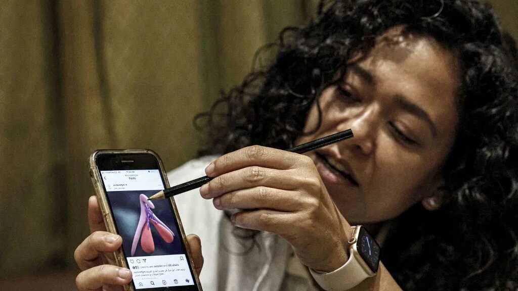 Reham Awwad, médecin, utilise une illustration sur un téléphone pour décrire la procédure de chirurgie de reconstruction clitoridienne à la clinique Restore FGM au Caire (AFP/Khaled Desouki)