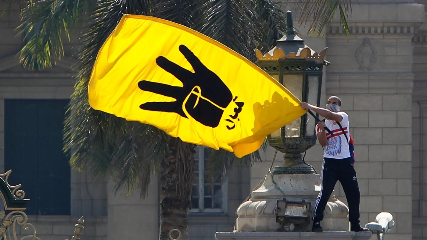 A supporter of Muslim Brotherhood and Egyptian former President Mohamed Morsi waves a yellow flag bearing the four-fingered Rabaa sign during a demonstration outside Cairo University on 14 May 2014 (Mohamed Abd El Ghany/Reuters)