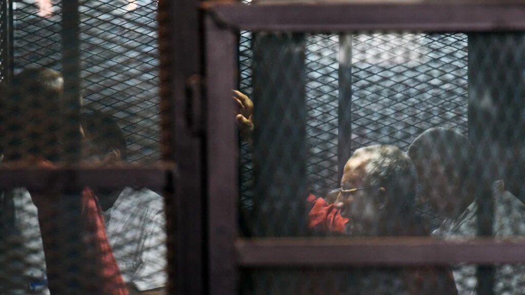 Egyptian Muslim Brotherhood leader Mohamed Badie (2nd-R) stands behind bars during a trial in Cairo in August 2015.