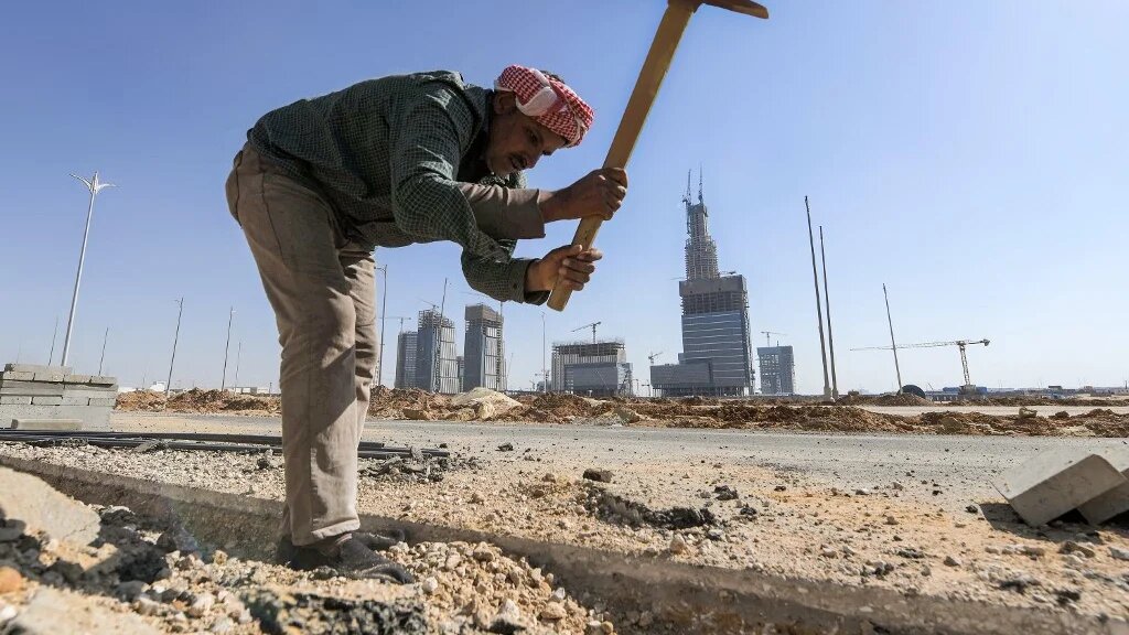 A workman digs with a pickaxe at a construction site at Egypt's "New Administrative Capital" megaproject, some 45 kilometres east of Cairo, on 7 March 2021 (AFP)