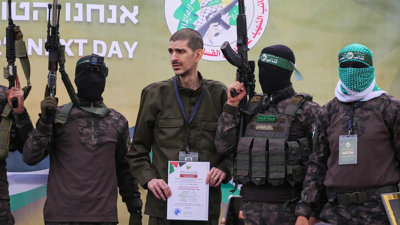 Hamas fighters escort Israeli captive Eli Sharabi on to a stage before handing him over to a Red Cross team in Deir al-Balah, central Gaza, on 8 February 2025 (AFP/Eyad Baba)