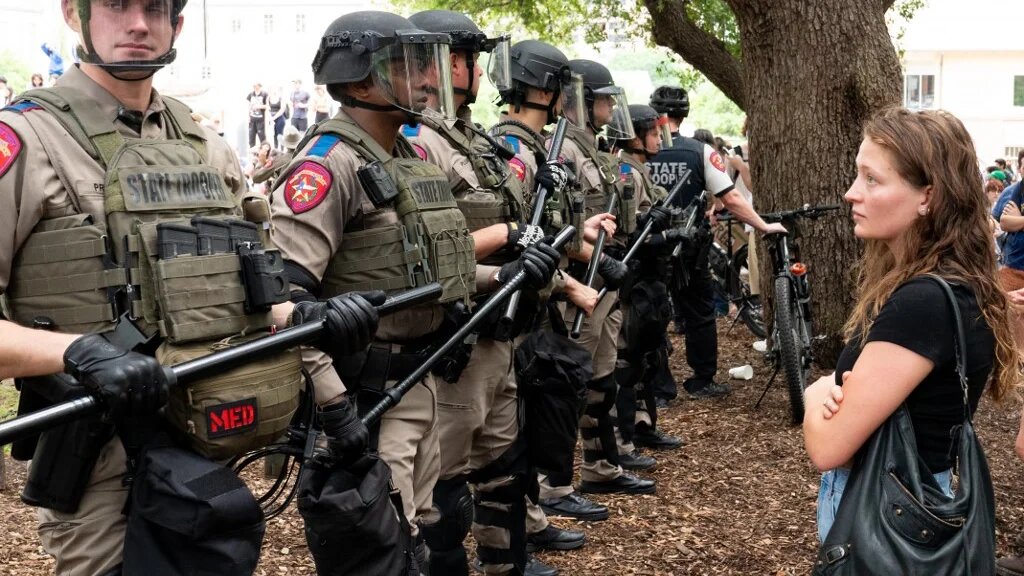 Une étudiante regarde une rangée de soldats de l’État du Texas alors que des étudiants propalestiniens manifestent contre la guerre sur le campus de l’université du Texas à Austin, aux États-Unis, le 24 avril 2024 (Suzanne Cordeiro/AFP)