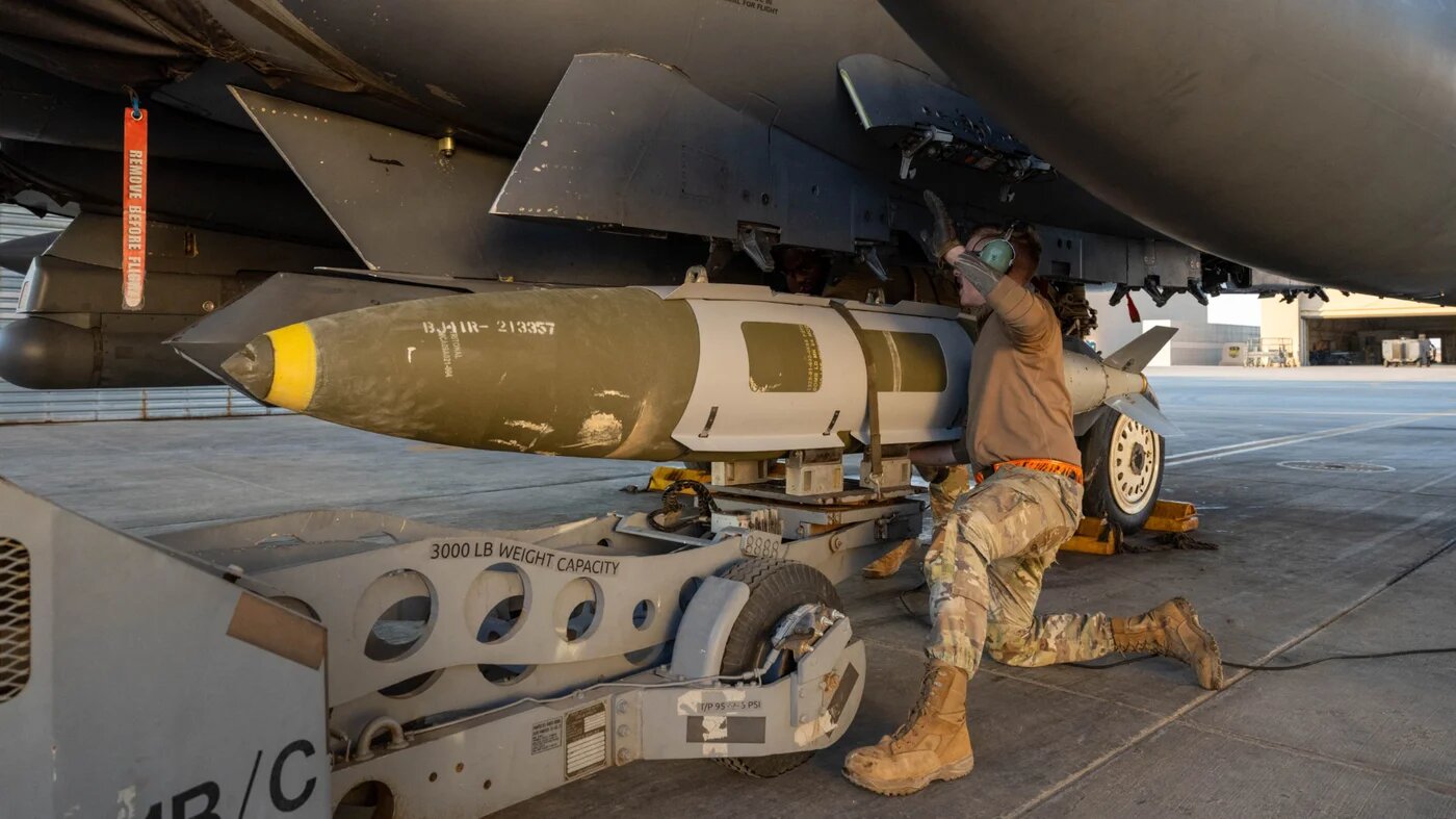 A US airman attaches a GBU-31 munition to an F-15E Strike Eagle in the US Central Command area of responsibility, in support of Operation Hawkeye Strike, 18 December 2025 (AFP/US Air Force) 