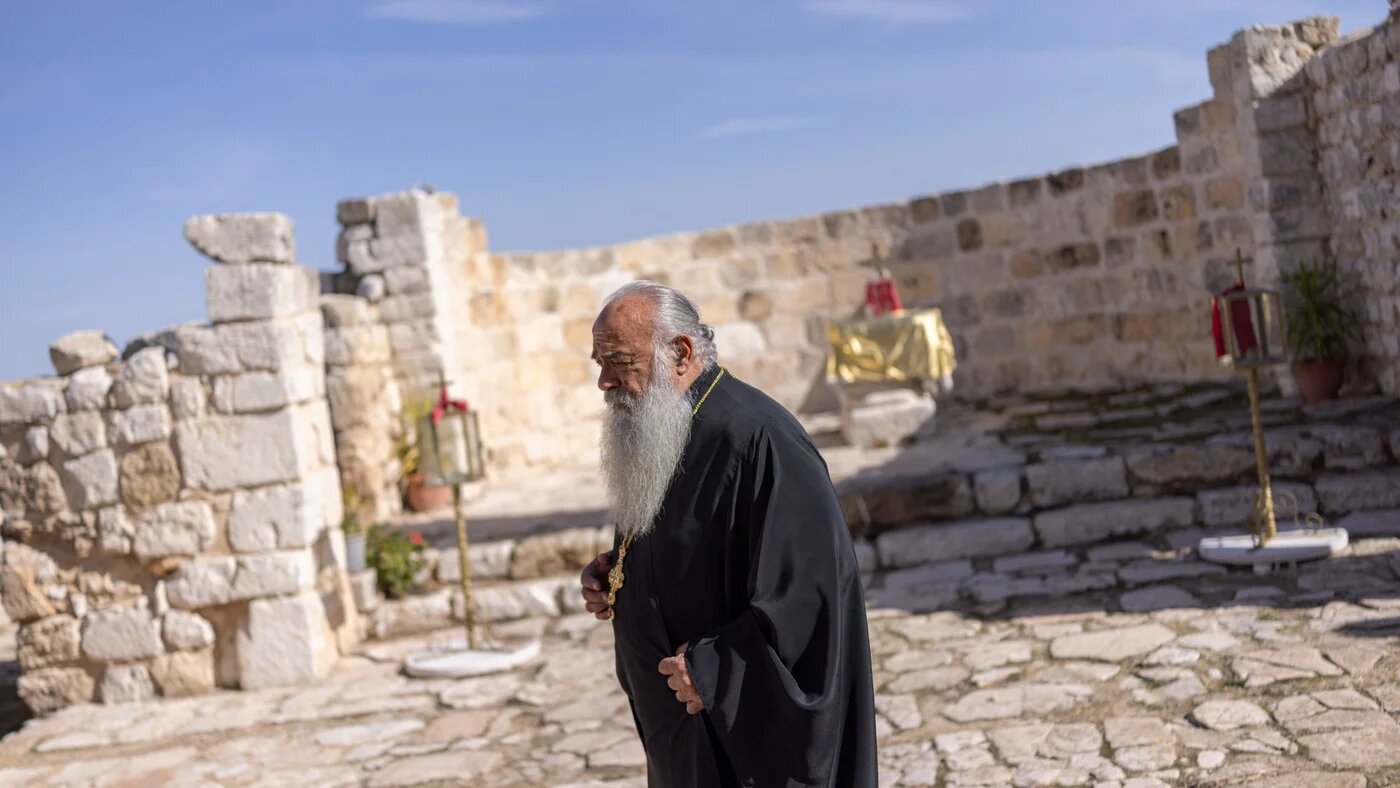 Priest Abouna Jack-Nobel Abed walks through the grounds of Saint George Greek Melkite Catholic Church in the mostly Christian town of Taybeh, in the Israeli‑occupied West Bank, days before Christmas festivities on 22 December 2025 (ILIA YEFIMOVICH/AFP)