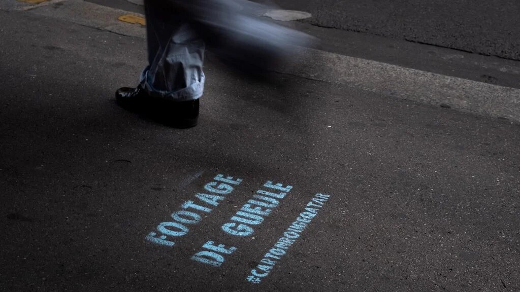Un piéton à Paris passe devant un graffiti d’une campagne contre la Coupe du monde de football 2022 au Qatar, à Paris, le 13 septembre 2022 (Joël Saget) 
