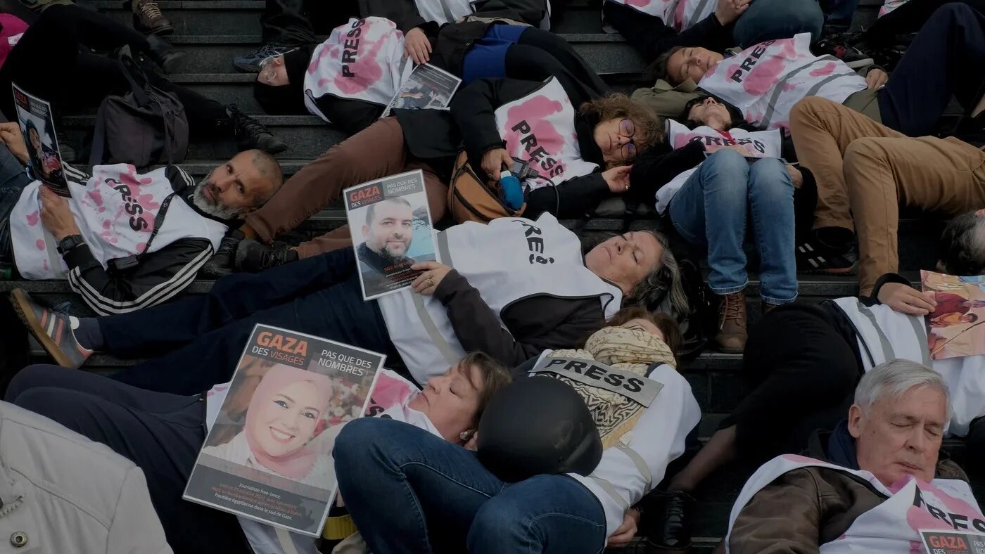 Protesters wearing jerseys reading "press" stage a die-in during a demonstration in support of Palestinian journalists in front of the Opera Bastille in Paris, on 16 April (Bilge Kotan/MEE)
