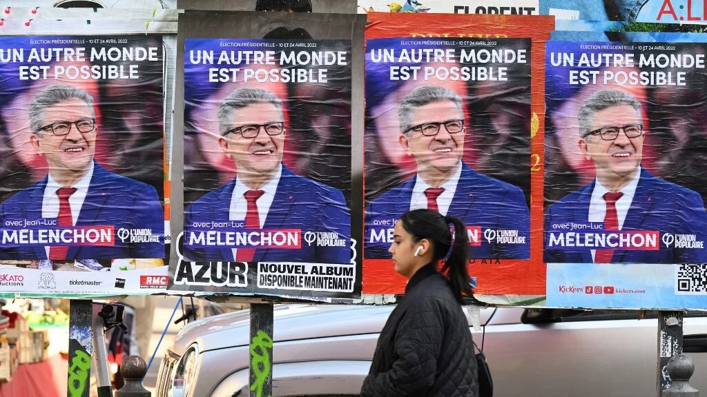 A woman walks past posters for French leftist presidential candidate Jean-Luc Melenchon in Marseille, southern France, on 31 March 2022 (AFP)