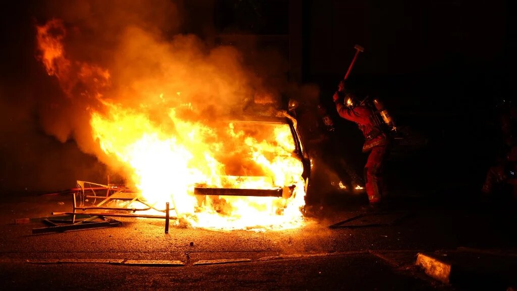 Un pompier tente de maîtriser l’incendie d’un véhicule brûlé par des manifestants en colère à Nanterre, le 27 juin 2023, après la mort d’un jeune automobiliste tué par la police (AFP/Zakaria Abdelkafi)