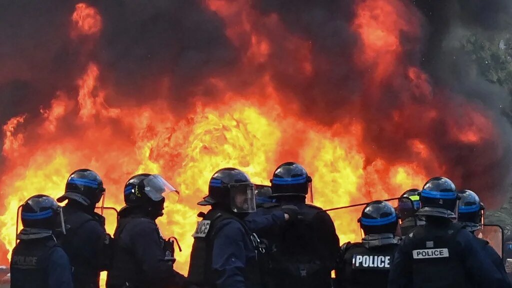 French police officers stand near a fire set by protesters during a demonstration in Montpellier, southern France, on 17 October 2026 (Sylvain Thomas/AFP)
