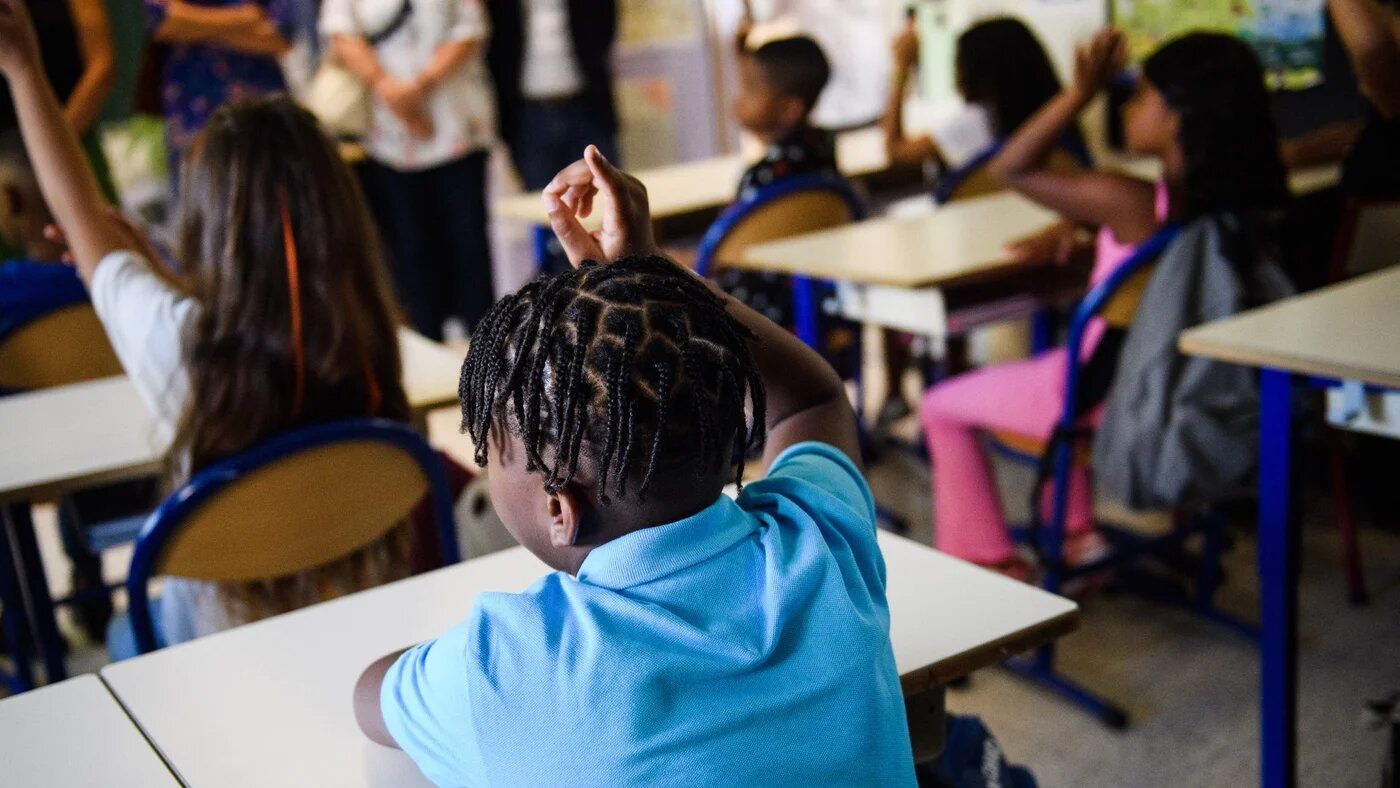 Students raise their hands at "Revolution Jet d'Eau" school in Marseille, southern France, on 1 September 2022 (AFP)
