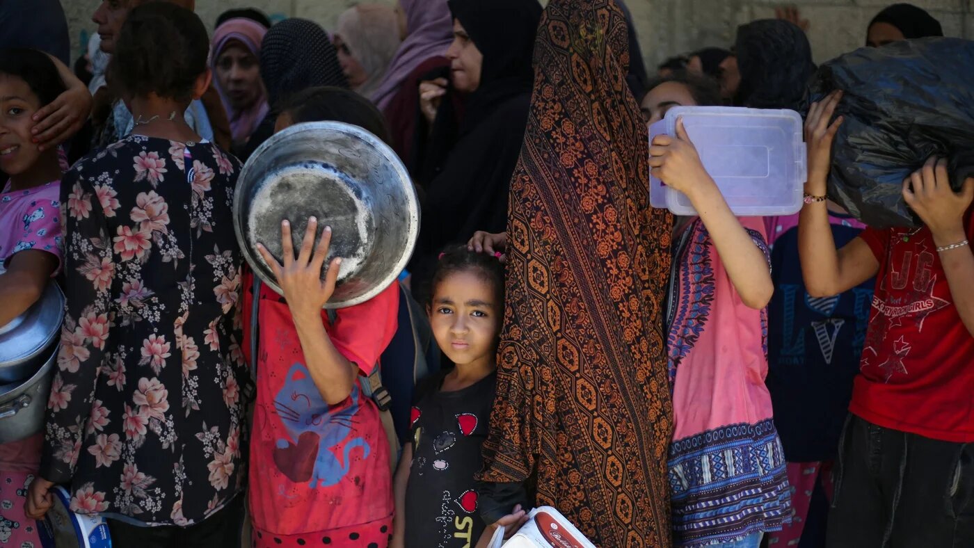 Palestinian children wait with others for food at a distribution point in Nuseirat, central Gaza Strip, on 2 June 2025 (AFP/Eyad Baba)