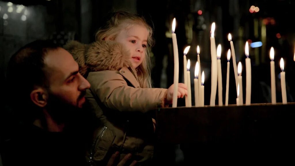 Un enfant palestinien allume des bougies lors d’une messe à l’église orthodoxe grecque Saint-Porphyre dans la ville de Gaza, le 7 janvier 2024, alors que l’offensive israélienne se poursuit à Gaza (AFP)