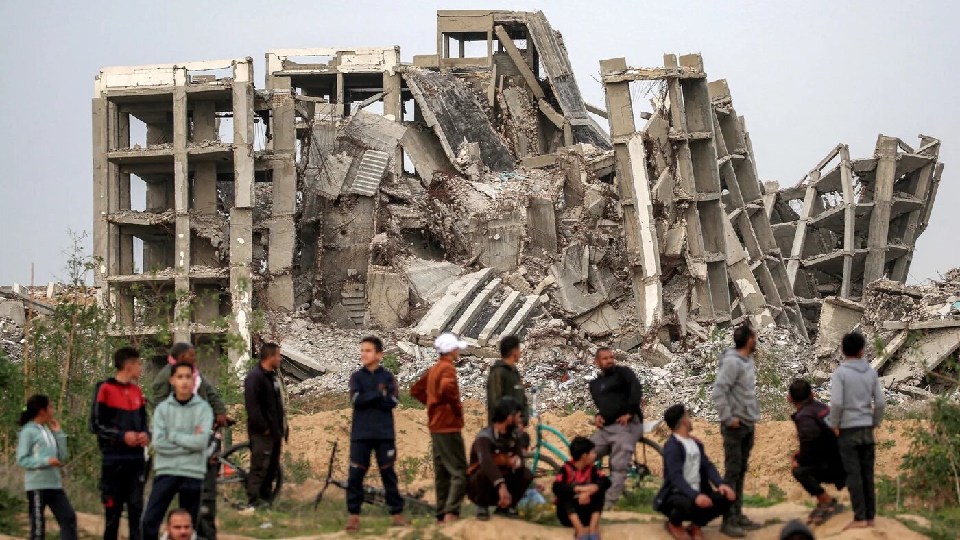People standing near destroyed buildings in the Zahra neighbourhood, southwest of Nuseirat in the central Gaza Strip, on 6 February 2026 (Eyad Baba/AFP)