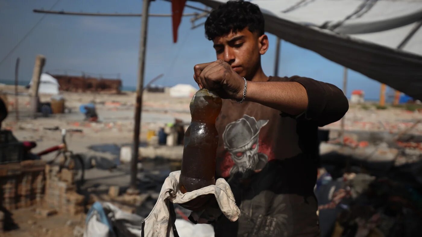 A Palestinian teen carrying bottle of fuel made from plastic (MEE/Mohammed al-Hajjar)