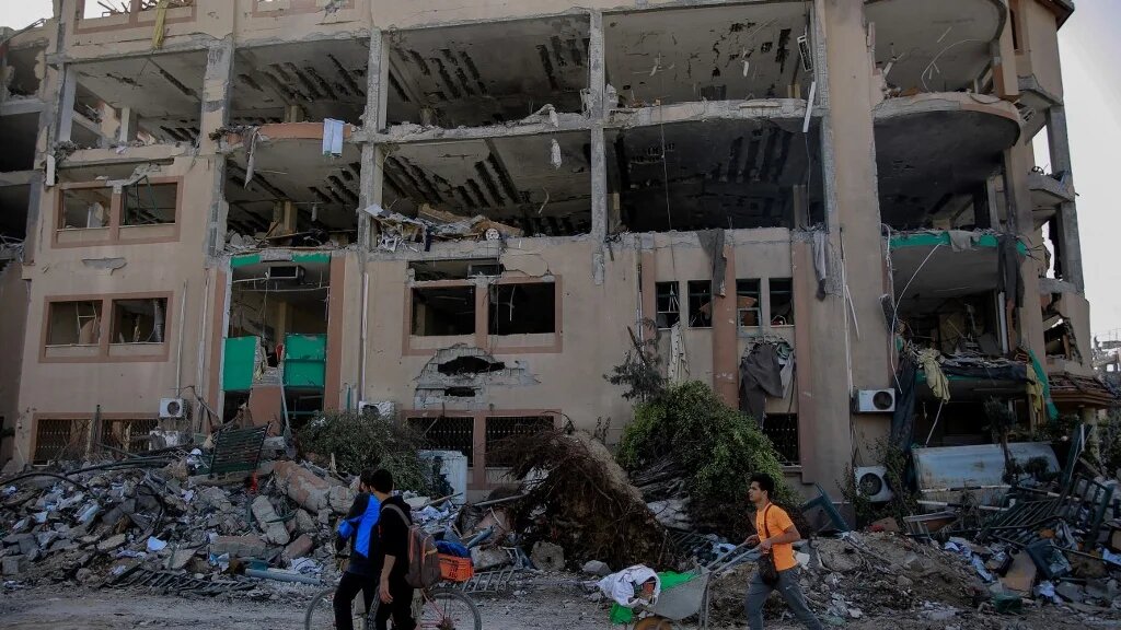 Palestinians walks past the destroyed building of the Islamic University in Gaza City on November 26, 2023, on the third day of a truce between Israel and Hamas (AFP)