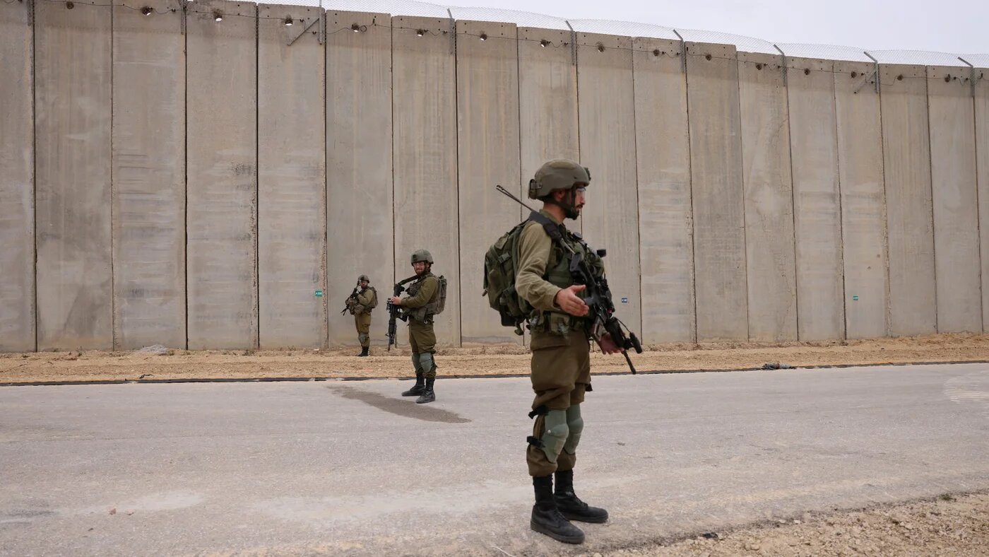 Israeli soldiers stand by the fence along the border with the Gaza Strip near Moshav Netiv HaAsara in southern Israel on 7 December 2021 (AFP)