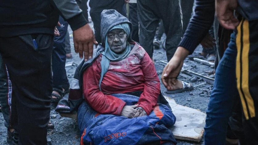 A woman injured in an Israeli strike sits amid the rubble in Rafah, Gaza, on 3 December 2023 (Said Khatib/AFP)