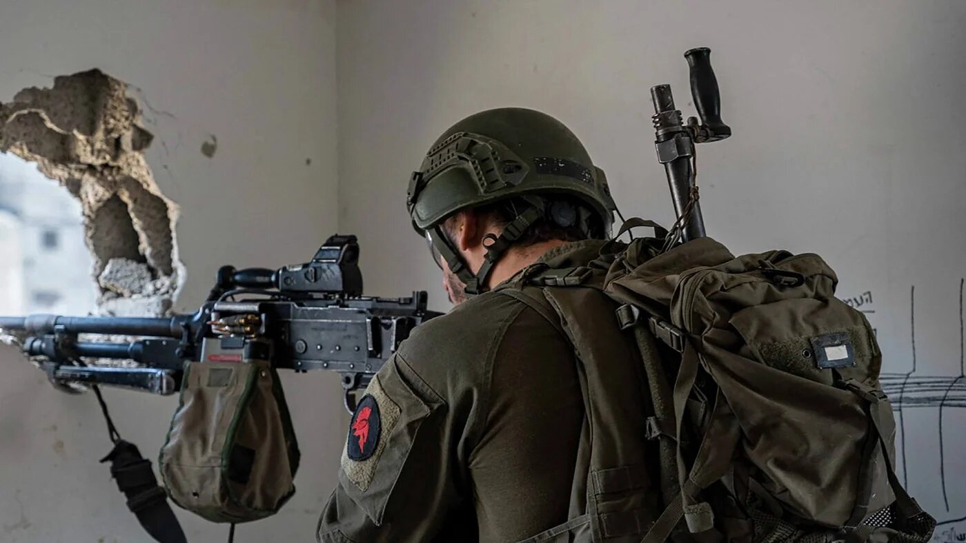 This handout picture released by the Israeli army on 5 March 2024 shows an Israeli soldier aiming his weapon in the Gaza Strip (Israeli Army / AFP)