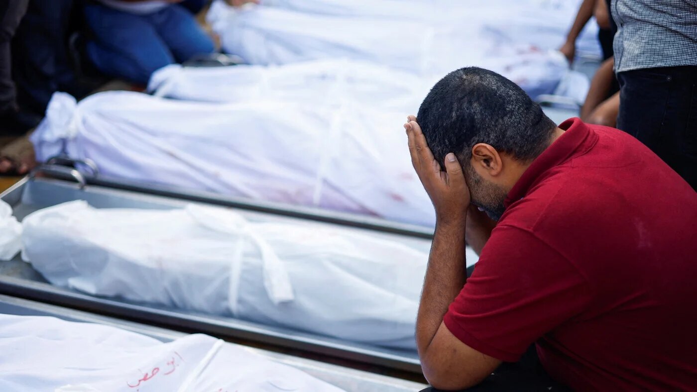 A man stands next to dead bodies killed in an Israeli air strike in Gaza's Khan Younis (Reuters)