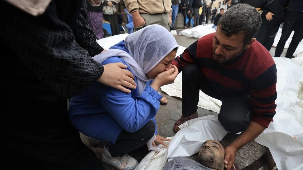 Palestinians mourn their relatives, killed in an overnight Israeli strike on the Al-Maghazi refugee camp, during a mass funeral at the Al-Aqsa hospital in Deir Al-Balah, in the central Gaza Strip, on 25 December 2023 (Mahmud HAMS/AFP)