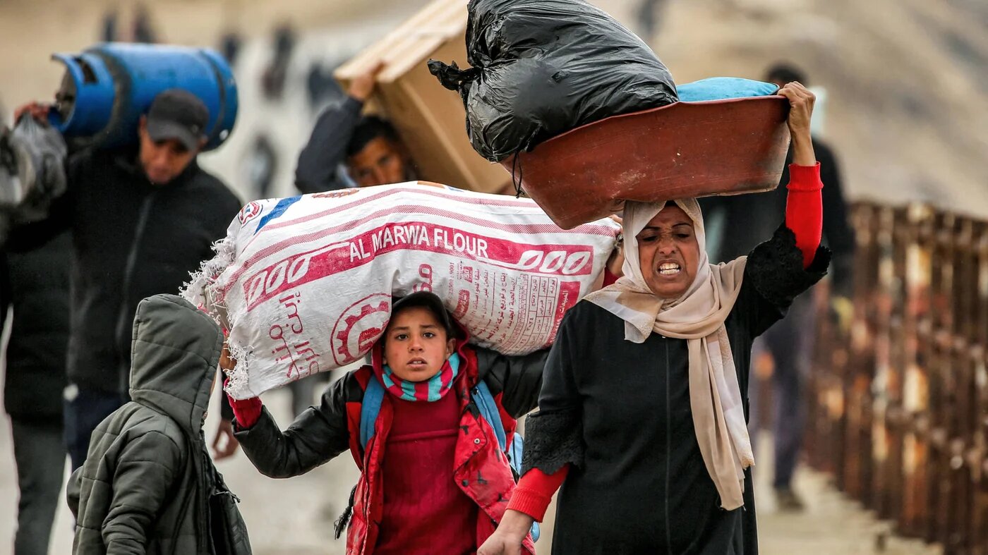 People walk with belongings along al-Rashid street between Gaza City and Nuseirat in the central Gaza Strip on 10 February 2025 as displaced people return home (AFP)