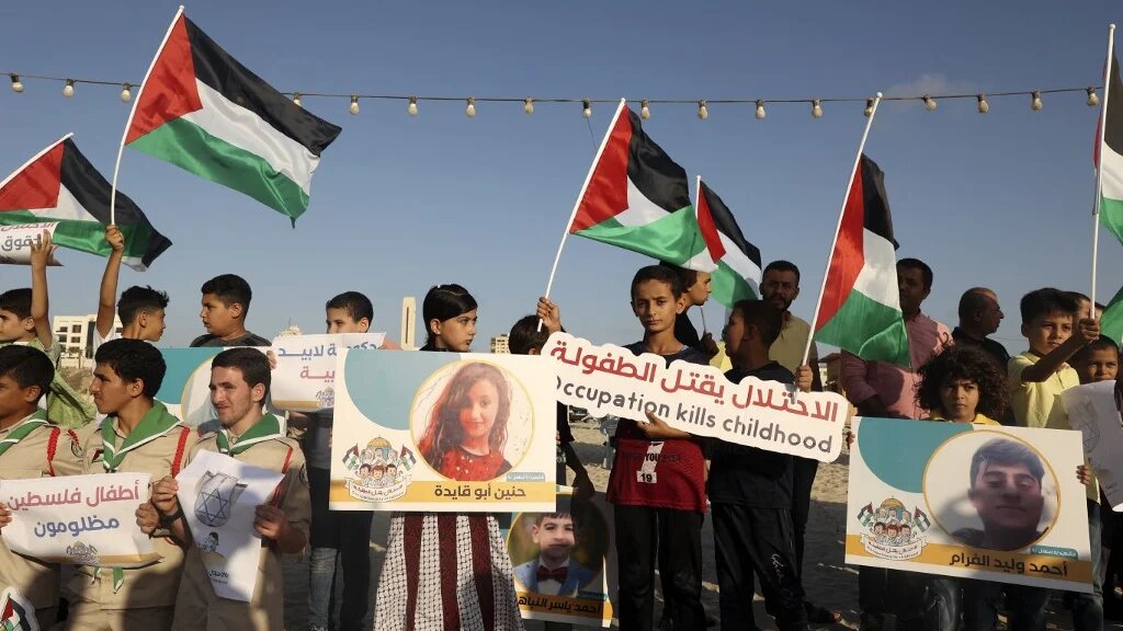 Scouts carrying Palestinian flags and pictures of children who were killed during the latest round of conflict between Israel and Gaza gather for a commemorative event, on 17 August 2022 (AFP)