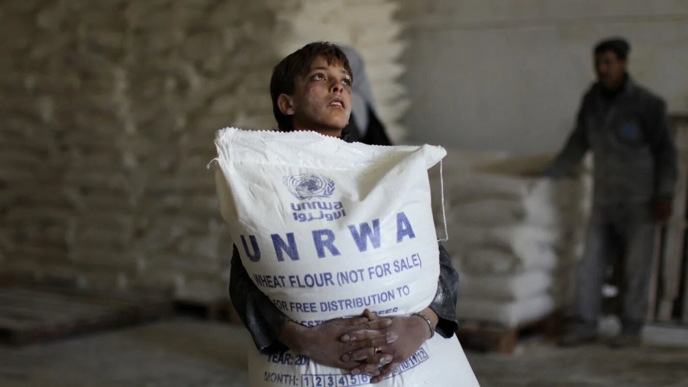 A Palestinian boy holds a sack of flour at a United Nations Relief and Works Agency (Unrwa) aid distribution centre in Gaza City in April 2013 (AFP)