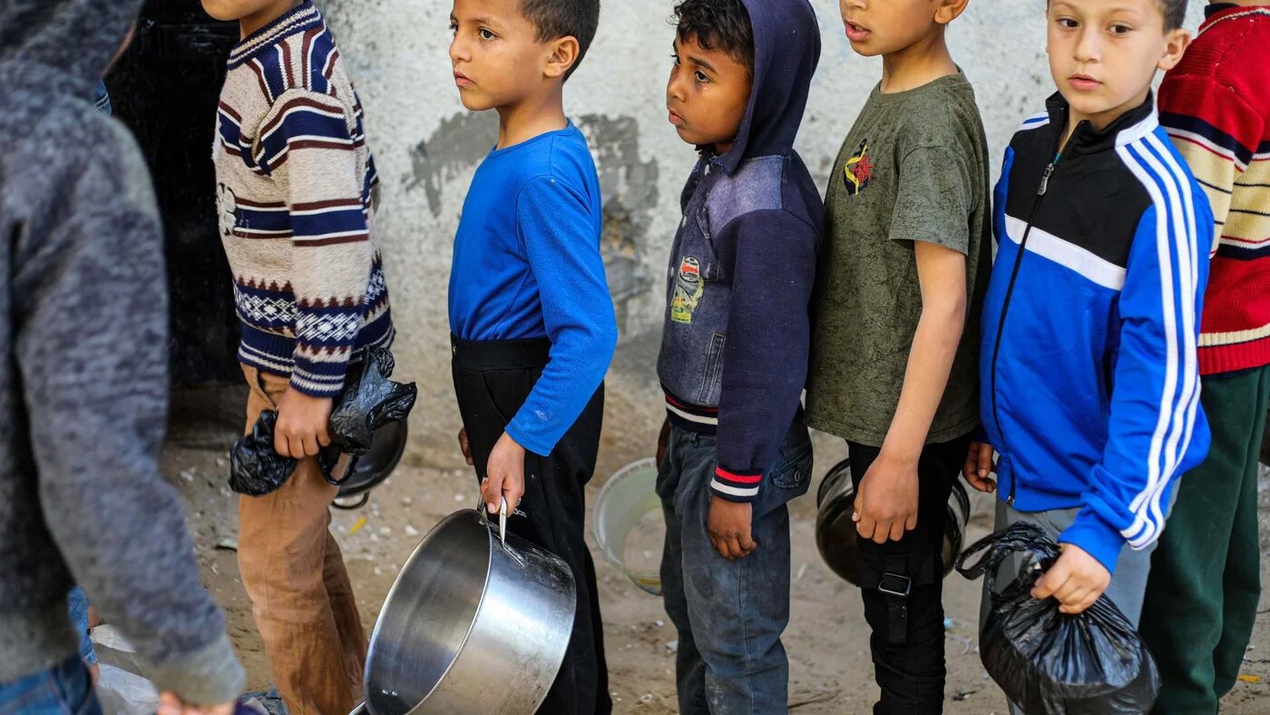 Children in Gaza's Al-Nuseirat refugee camp queue for soup provided by a charity during Ramadan, in April 2022 (Reuters)