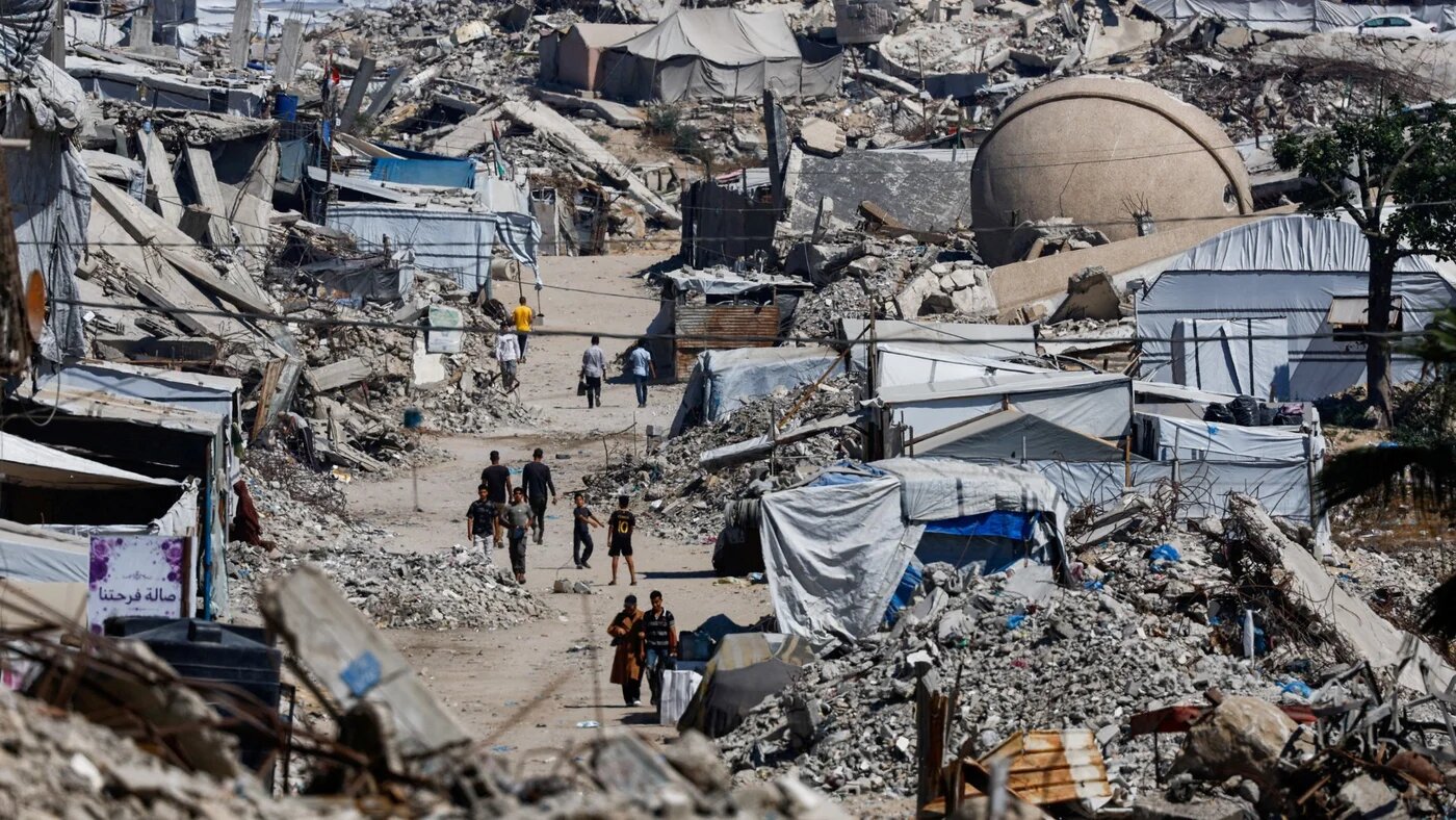 Palestinians walk past the rubble of residential buildings destroyed during the war, at the Jabalia refugee camp in the northern Gaza Strip, 12 June 2026 (Reuters/Mahmoud Issa)