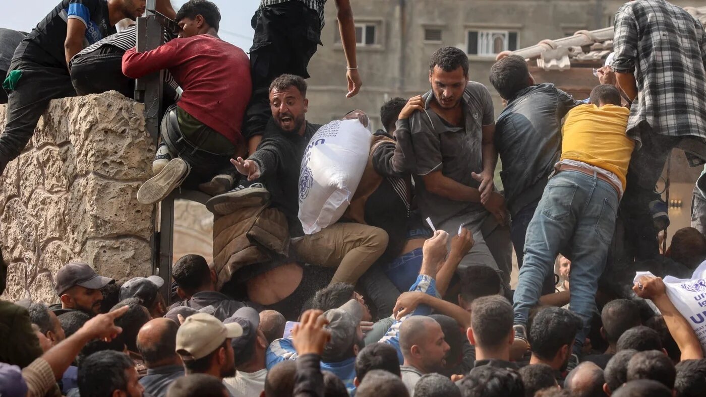 People scramble to receive sacks of flour at a Unrwa aid distribution centre in Deir al-Balah in the central Gaza Strip on 3 November 2024, amid the ongoing Israeli war on Gaza (Eyad Baba/AFP)