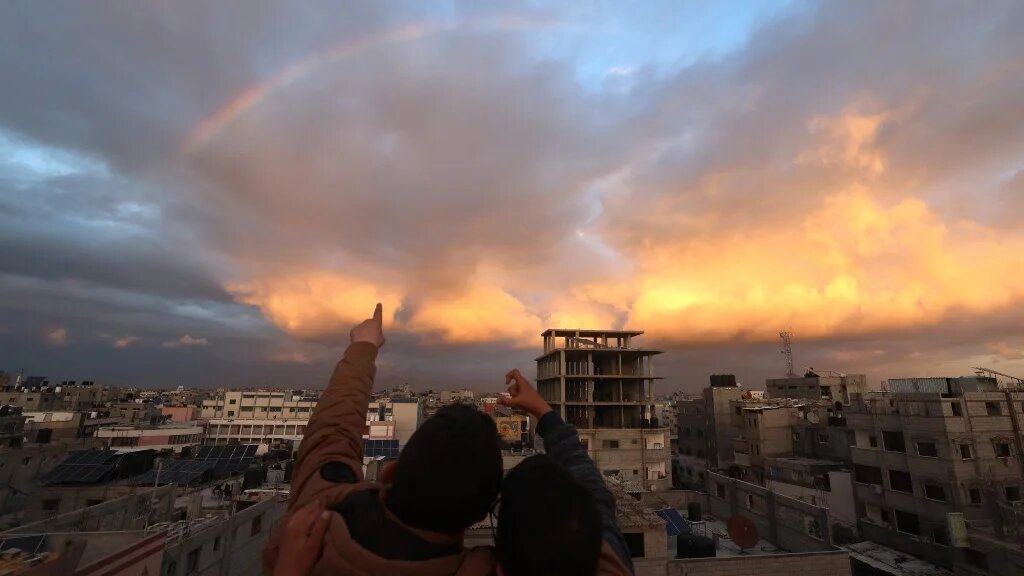 Des enfants regardent un arc-en-ciel au-dessus de Rafah, alors qu’Israël continue ses raids sur la bande de Gaza (AFP)