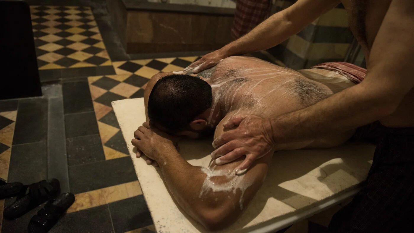 A man in Hammam al-Malik al-Zahir is washed on a marble platform (MEE/Hasan Belal)