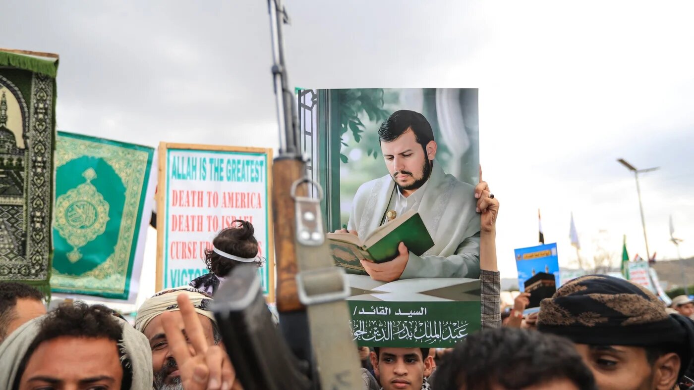 Supporters of the Houthi authorities brandish their weapons and hold up a portrait of the group's leader, Abdul Malik al-Houthi, during a protest against the Saudi intervention in Yemen and against Saudi Arabia's recent accusation that the Houthis fired at the holy city of Mecca, in Sanaa on 18 September 2026 (AFP)