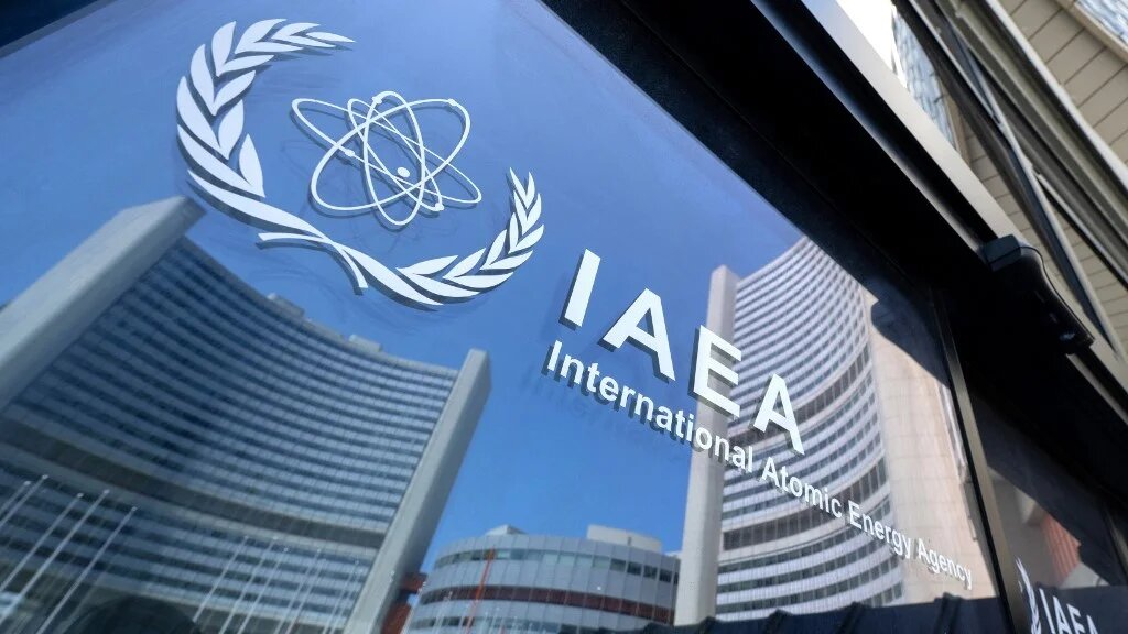 Buildings of the International Atomic Energy Agency’s headquarters are reflected in doors featuring the agency’s logo in Vienna, Austria, on 13 June 2025 (Joe Klamar/AFP)