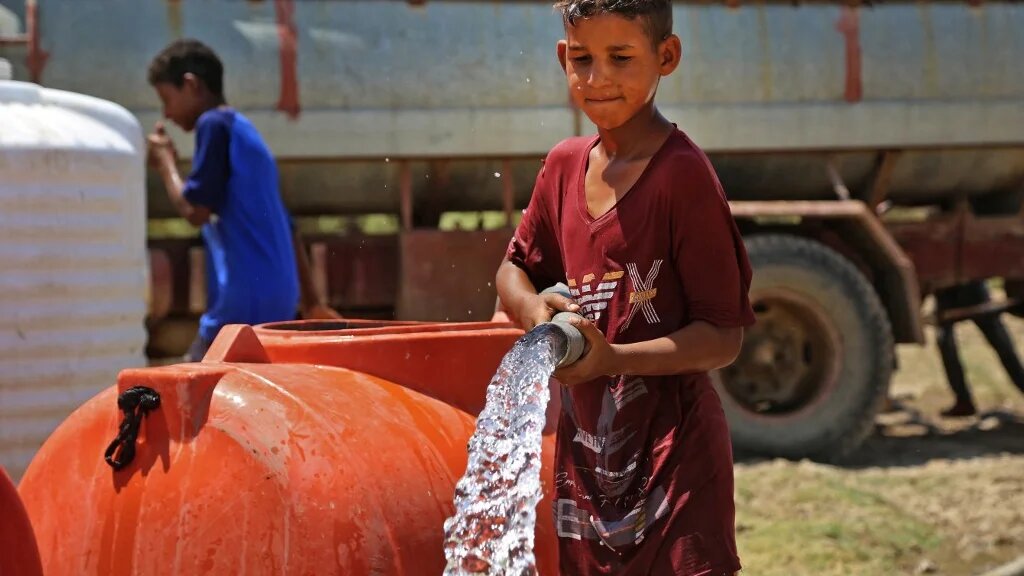 Un garçon puise de l’eau dans une citerne dans le village d’al-Aghawat, dans la province centrale de Diwaniya, en Irak, le 18 juillet 2022 (AFP/Haïdar Indhar)