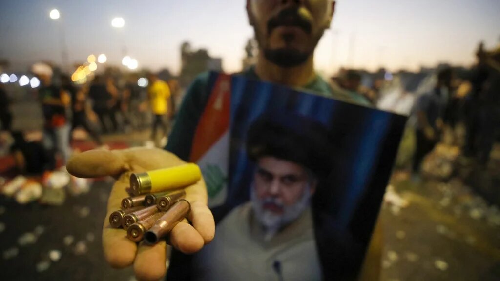 Un partisan du religieux chiite irakien Moqtada Sadr montre des douilles et une cartouche de fusil de chasse dans la capitale Bagdad, le 29 août 2022 (AFP/Ahmad Al-rubaye)