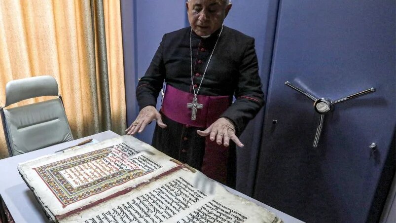 L’archevêque chaldéen de Mossoul Michaeel Najeeb présente un ancien codex chrétien en langue syriaque au Centre numérique des manuscrits orientaux à Erbil, le 16 mai 2023 (AFP/Safin Hamid)