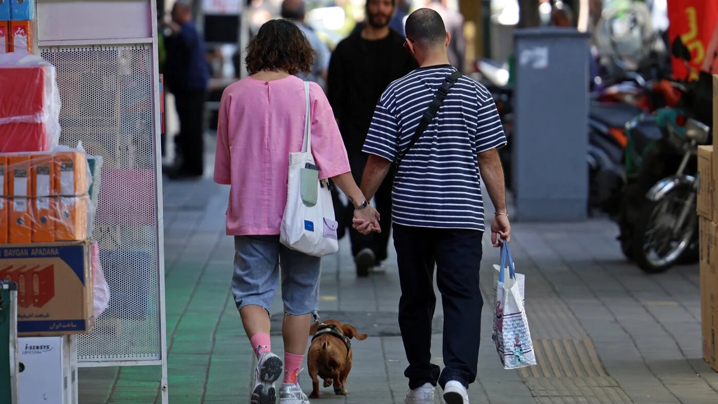 An Iranian couple walks along a busy street in Tehran on 25 April 2026 (AFP)