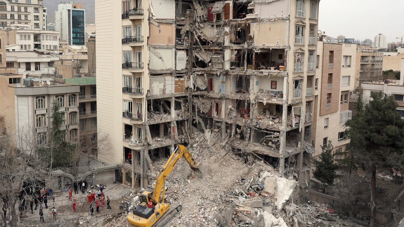 An excavator clears rubble from destroyed residential buildings in northern Tehran on 23 March 2026 (AFP)