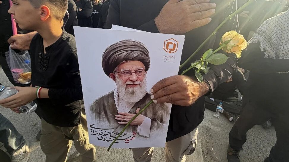 A mourner holds a flower and a portrait of Iran’s slain supreme leader, Ayatollah Ali Khamenei, at the start of his funeral ceremonies in Tehran on 4 July 2026 (Atta Kenare/AFP)