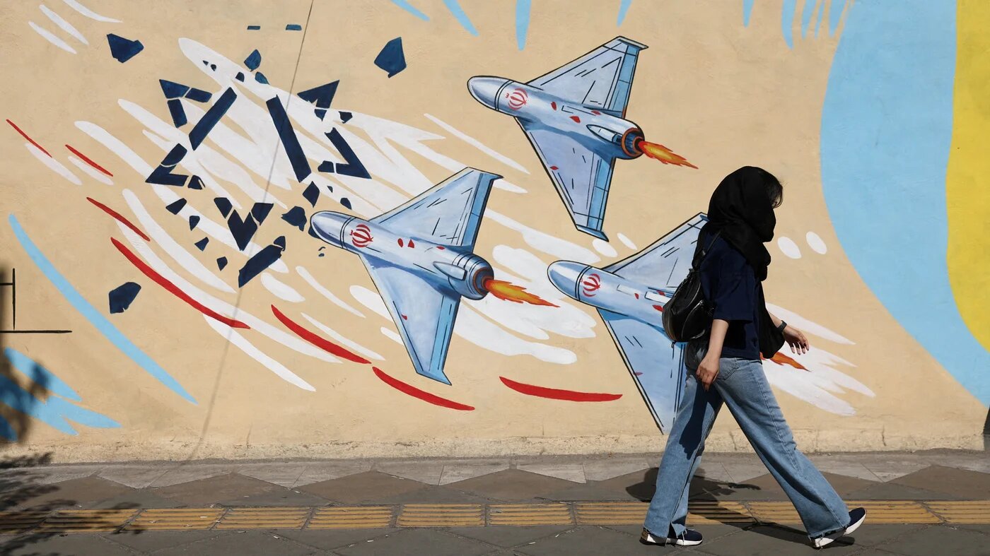 An Iranian woman walks next to an anti-Israeli mural on a street in Tehran, 8 June, 2026. (Majid Asgaripour/WANA (West Asia News Agency/Reuters)