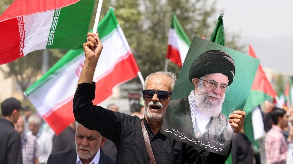 A demonstrator carries a portrait of Iranian Supreme Leader Ayatollah Ali Khamenei during a rally condemning Israeli and US aggression, in Tehran on 25 July 2025 (AFP)