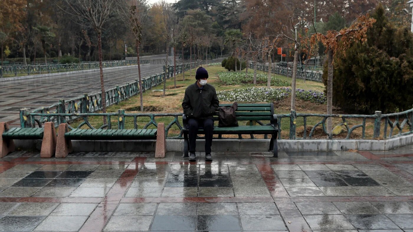 A man sits in Mellat Park in Tehran on 1 December 2025 as the first winter showers soak the Iranian capital after one of the driest years (AFP)