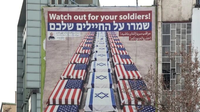 An anti-US and anti-Israel banner hangs on a building in Tehran on 27 January 2026, as a US naval strike group has deployed to Middle Eastern waters (Atta Kenare/AFP)